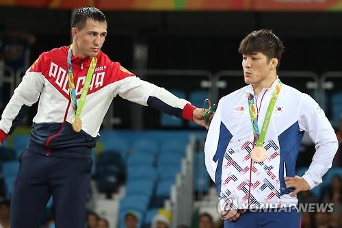 Roman Vlasov of Russia (L) reaches out to Kim Hyeon-woo (R) during the medal ceremony for the men's 75kg Greco-Roman wrestling event at the Rio de Janeiro Olympics on Aug. 14, 2016. Vlasov beat Kim in a controversial finish in the round of 16, relegating Kim to the bronze medal contest.