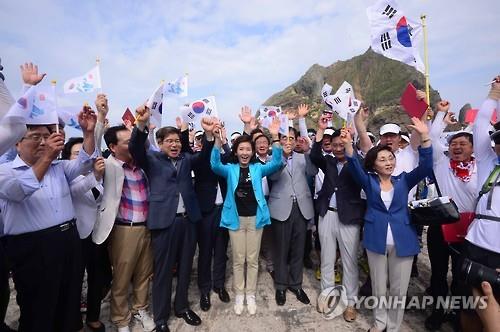 South Korea's lawmakers and other participants give three cheers while waving the national flag during their visit to the easternmost islets of Dokdo on Aug. 15, 2016.