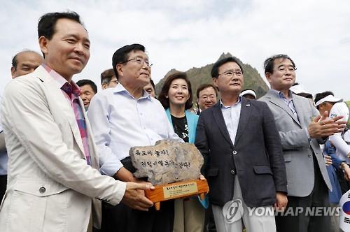 Taean County head Han Sang-ki (2nd from L) delivers a stone from South Korea's westernmost island to Ulleung County head Choi Soo-il (2nd from R) during their visit to the nation's easternmost islets of Dokdo on Aug. 15, 2016.
