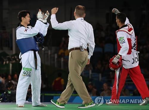 South Korean taekwondo fighter Lee Dae-hoon (L) applauds his opponent, Ahmad Abughaush of Jordan, after Abughaush beat him 11-8 in the quarterfinals of the men's -68kg at the Rio de Janeiro Olympics on Aug. 18, 2016.