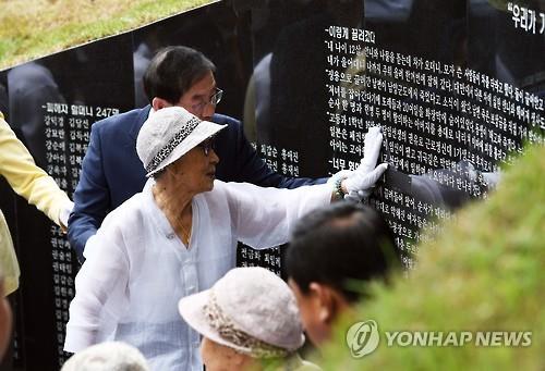 Former sex slave Kim Bok-dong (R) and Seoul Mayor Park Won-soon touch a memorial where testimonies of "comfort women" are written at the newly opened memorial park on Mount Nam, central Seoul, on Aug. 29, 2016. 