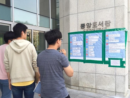 Students look at posters put up outside a library by a student council of Seoul's Yonsei University on Sept. 1, 2016. The student council revealed a group chat of 30 male students verbally harassing fellow female students. 