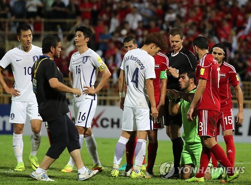 South Korean players (in white) show their frustration as Syrian goalkeeper Ibrahim Alma (in green) stays on the pitch to delay their Asian World Cup qualifying match at Tuanku Abdul Rahman Stadium in Seremban, Malaysia, on Sept. 6, 2016.