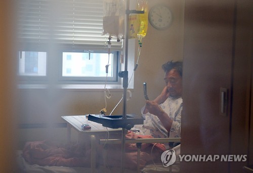 Saenuri Party Chairman Lee Jung-hyun, admitted to a Seoul hospital after a weeklong hunger strike, looks at his cell phone at his hospital room on Oct. 3, 2016.