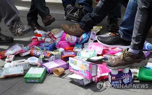 A group of victims of toxic humidifier sterilizers and civic activists tramples products made by the local unit of Britain's Reckitt Benckiser at a press conference in western Seoul on April 28, 2016, calling for citizens to join their boycott.