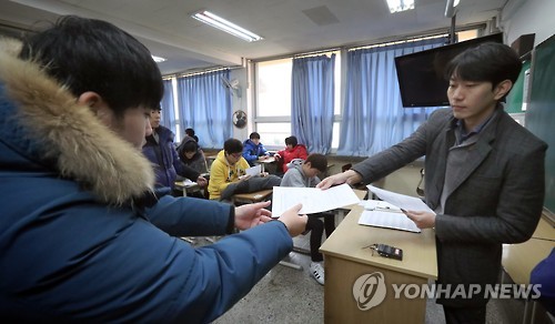 A high school senior receives his score on the state-administrated scholastic aptitude test from his homeroom teacher at Yeouido High School in Seoul on Dec. 7, 2016. High scores on the test, administered last month, boost students' chances of entering the university of their choice.