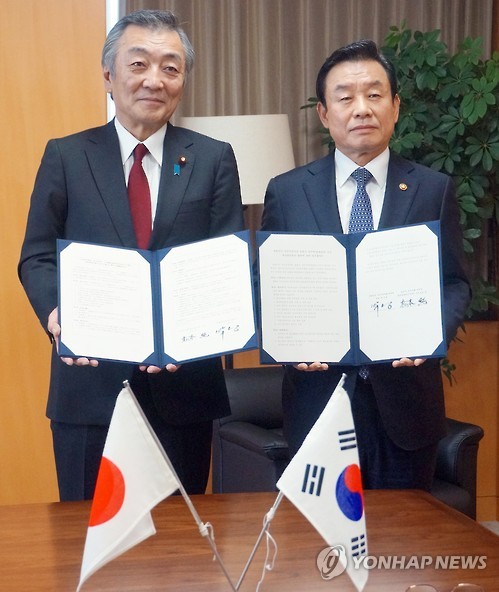 In this photo provided by the Ministry of Public Safety and Security, Minister Park In-yong (R) poses for a photo with his Japanese counterpart Jun Matsumoto in Tokyo on Dec. 12, 2016, after signing an agreement to boost cooperation in disaster control. 