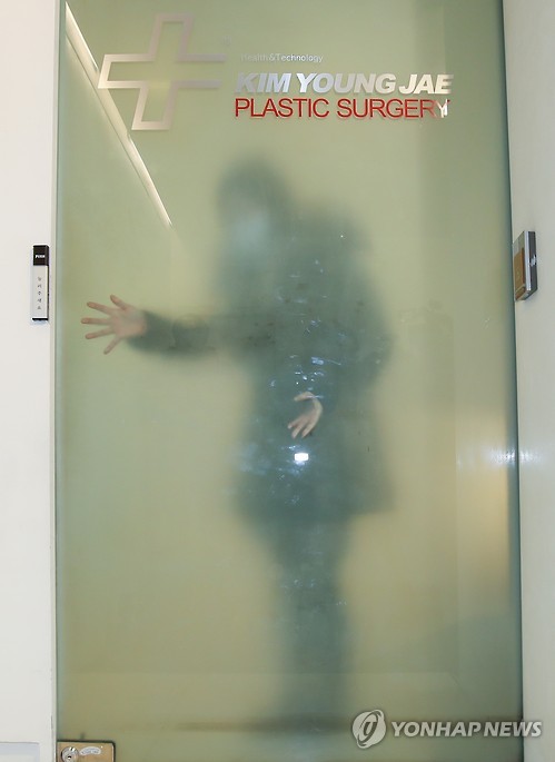 An employee at plastic surgeon Kim Young-jae's office in Seoul is visible through a glass door as independent counsel team investigators arrive for a search on Dec. 28, 2016. Kim's office was one of the cosmetic surgery clinics raided on that day as part of the ongoing probe into allegations related to President Park Geun-hye and her confidante Choi Soon-sil. Kim is believed to have provided treatment to the president with Choi's help without going through due security procedures. 