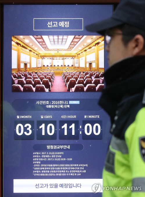 This photo, taken on March 8, 2017, shows a police officer standing next to a notice posted at the entrance to the Constitutional Court in Seoul about a ruling on the impeachment of President Park Geun-hye that the court will make at 11:00 a.m. on March 10. The announcement will be broadcast live from the main courtroom.