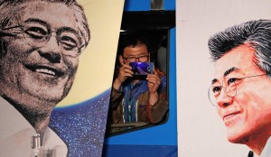 A supporter takes pictures between pictures of the South Korean President-elect Moon Jae-In, as Moon speaks to his supporters after he was declared the winner of the election South Korea, May 10, 2017. Credit Jeon Heon-Kyun/European Pressphoto Agency