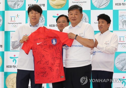 South Korea's national football team head coach Shin Tae-yong (L) holds the national football team jersey with Roh Tae-kang, the second vice minister of the Ministry of Culture, Sports and Tourism, at an event to promote reservations of commemorative coins for the 2018 PyeongChang Olympics at the KEB Hana Bank headquarters in Seoul on Sept. 11, 2017. (Yonhap)