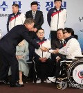 South Korean President Moon Jae-in (L) shakes hands with wheelchair curler Bang Min-ja during the South Korean squad launch ceremony for the PyeongChang Paralympics in Seoul on March 2, 2018. (Yonhap)