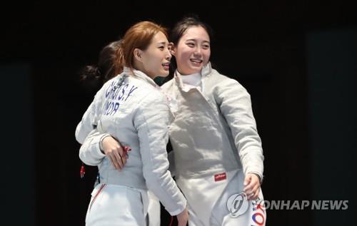 South Korean sabre fencers Choi Soo-yeon (L) and Yoon Ji-su celebrate their women's team gold medal over China at the 18th Asian Games at Jakarta Convention Center (JCC) Cendrawasih Hall in Jakarta on Aug. 22, 2018. (Yonhap)