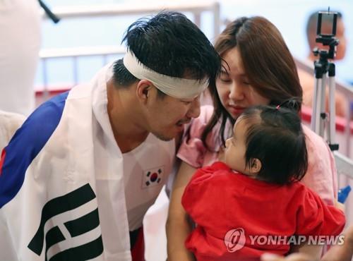 South Korean Greco-Roman wrestler Cho Hyo-chul enjoys a tender moment with his wife Kim Young-jin and daughter Seo-yoon after winning gold medal in the men's 97kg class at the 18th Asian Games in Jakarta on Aug. 22, 2018. (Yonhap)