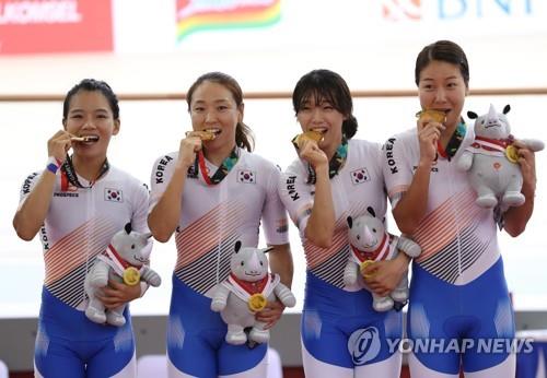 From left: South Korean cyclists Lee Ju-mi, Na Ah-reum, Kim Hyun-ji and Kim You-ri bite their gold medals won in the women's team pursuit track cycling event at the 18th Asian Games at Jakarta International Velodrome on Aug. 28, 2018. (Yonhap)