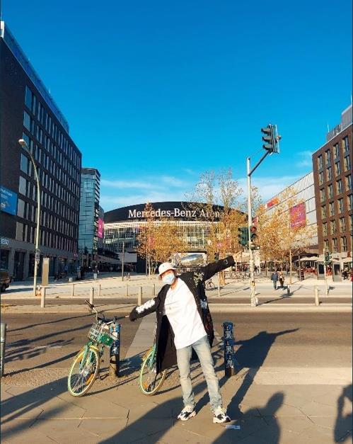 This image captured from BTS's official Twitter account on Oct. 16, 2018, shows a masked band member posing in front of the Mercedes-Benz Arena in Berlin, Germany. (Yonhap)