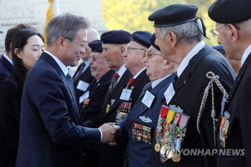 South Korean President Moon Jae-in (L) shakes hands with a French Korean War veteran during an official welcome ceremony held in Paris on Oct. 15, 2018, to mark his four-day state visit to France. (Yonhap)