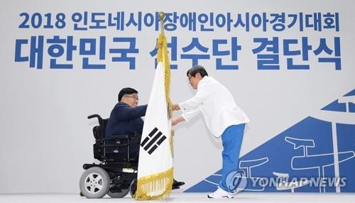 This file pool photo taken on Sept. 19, 2018, shows Korea Paralympic Committee (KPC) President Lee Myung-ho handing the national flag to Jun Min-sik, South Korea's chef de mission for the Asian Para Games in Indonesia, at the national team launching ceremony in Icheon, Gyeonggi Province. (Yonhap)