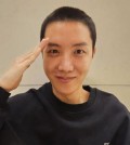 This photo captured from Hybe's Weverse fan community platform shows J-Hope of K-pop boy group BTS giving a salute with a buzz cut. (PHOTO NOT FOR SALE) (Yonhap)