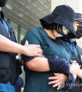 Murder suspect Jung Yoo-jung, wearing a hat and a mask, leaves a police detention center en route to the prosecution in Busan on June 2, 2023. (Yonhap)
