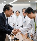 President Yoon Suk Yeol (2nd from L) shakes hands with a doctor at Asan Medical Center in Seoul on March 18, 2024, in this photo provided by the presidential office. (PHOTO NOT FOR SALE) (Yonhap)
