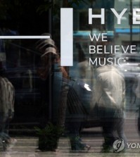 Pedestrians' reflections are seen in the window of the Hybe building in Yongsan, Seoul, on May 10, 2024. (Yonhap)