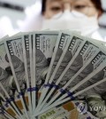 An official checks banknotes at a bank branch of Hana Bank in central Seoul, in this file photo taken March 4, 2020. (Yonhap)